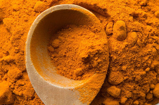 Turmeric powder and Wooden Measuring Spoon Pile of turmeric on white background with wooden measuring spoon